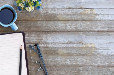 Boş kağıt defter, gözlük, kalem ve kahve kahverengi ahşap masa arka plan üzerinde. Üstten Görünüm kopya alanı (seçici odak) ile. Ofis Resepsiyon Masa kavramı.