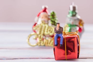Minyatür insanlar: hediye kutusu ile oturan işadamı rakamlar Noel dekorasyon arka plan bulanık. para ve mali kavramı. Noel ve yılbaşı konsept olarak kullanmak için alan kopyalama.
