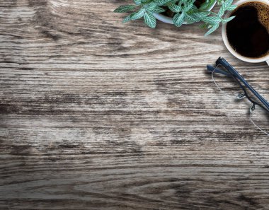 Ofisteki ahşap arka planda çiçekli, bardaklı ve kahveli ahşap masa..