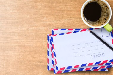 Üstten görünüm fincan kahve ve siyah kalem ofis iş yerinde ahşap masa üzerinde hava posta zarflarla