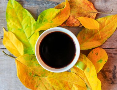 Eski ahşap masa üzerinde sonbahar yaprakları ile kahve fincan üstten görünüm