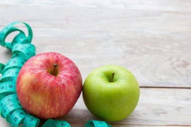 Sağlıklı yaşam konsepti ile elma. Kilo kaybı veya diyet kavramı. Kırmızı elma ve yeşil ahşap masa arka plan kopya alanı tasarım ile kasette ölçmek