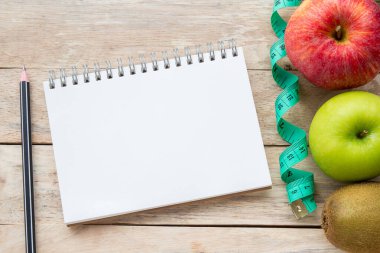 Bant, elma, kalem ve defter ahşap masa arka plan üzerinde ölçüm ile üstten görünüm. Diyet ve sağlık, beslenme ve sağlık sigortası kavramı