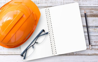 Güvenlik Mühendisi kask, defter, gözlük ve kalem Beyaz ahşap zemin üzerinde.