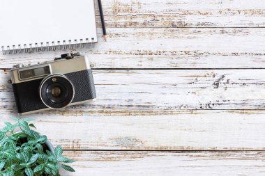 Vintage fotoğraf makinesi, defter, kalem ve taze çiçek ile ofis Resepsiyon ahşap masaları. Üstten Görünüm kopya alanı ile. Üst eski fotoğraf makinesi Beyaz ahşap masa üzerinde görüntüleyin. Retro vintage filtre.