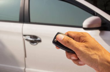 Arabanın anahtarını tutan adam, bulanık arka planı olan yeni bir arabayı çalıştırmaya hazır. Anahtarı bulanık araba parkında tut. soyut arkaplan