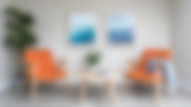 Canlı turuncu sandalyelerin, minimalist dekorun ve rahatlatıcı soyut sanatın bulunduğu şık, modern bir oturma odası. Çağdaş ev tasarımı için mükemmel..