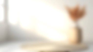 Yumuşak güneş ışığıyla aydınlatılan basit bir vazoda kurumuş çiçeklerin sergilendiği sakin ve minimalist bir iç mekan, sıcak ve davetkar bir atmosfer yaratıyor..