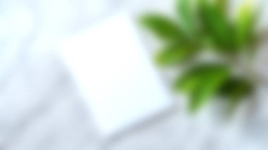 Yeşil yaprakların yanındaki boş bir kağıt parçasına yumuşak bir odak içeren sakin bir kompozisyon, sakinleştirme arkaplanı veya yaratıcı tasarım projeleri için ideal.