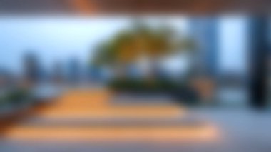 Yumuşak akşam ışığıyla aydınlatılan ve şehrin ufuk çizgisine karşı sakin bir ortam yaratan, ağaçla modern mimarinin yer aldığı sakin bir açık alan..