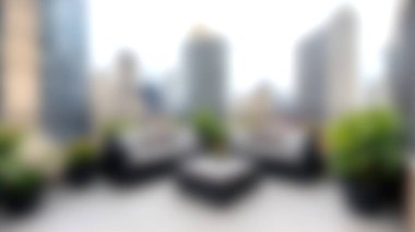 Modern bir terasın bulanık manzarası yeşillik ve şehir binalarını sergiliyor ve sakin bir şehir kaçışı yaratıyor. Rahatlamak ve rahatlamak için ideal..