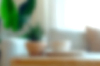 Yumuşak doğal ışığın, yeşil bitkilerin ve ahşap bir masanın olduğu güzel düzenlenmiş bir oturma odası. Ev ortamlarında sakinleştirici bir atmosfer yaratmak için ideal.