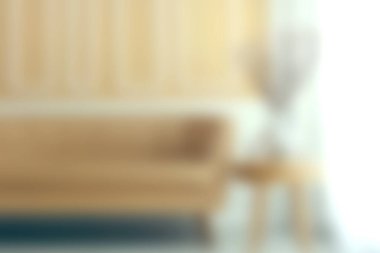 Şık bir oturma odası, hafif güneş ışığıyla aydınlatılmış minimalist dekorlu rahat bir kanepeyi yakalar. Yumuşak renkler ve dokular dinlenmek için mükemmel bir atmosfer yaratıyor..