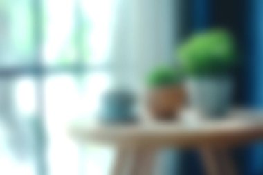 Saksı bitkileriyle dolu bulanık bir masa içeren huzurlu ve rahat bir ortam. Rahatlamak için mükemmel bir ortam yaratan doğal ışık..