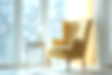 Doğal ışıkla aydınlatılmış yumuşak bulanık bir sandalyenin olduğu rahat bir oturma odası sahnesi. Bu davet edici alan modern iç tasarım elementlerini sergiliyor ve rahatlamak için mükemmel sıcak, sakin bir atmosfer yaratıyor..