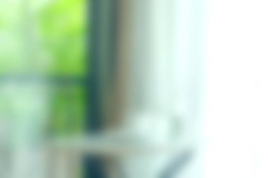 Bu görüntüde parlak ve havadar bir iç mekan var. Dışarıdaki yumuşak bulanık elementler ve yeşillik de dahil olmak üzere doğal ışık pencereden içeri akıyor..