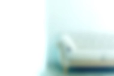 Minimalist bir oturma odasına yerleştirilmiş yumuşak odaklı zarif bir kanepeyi gösteren sakin bir görüntü. Mekanın şık tasarımını ve rahat atmosferini vurguluyor..