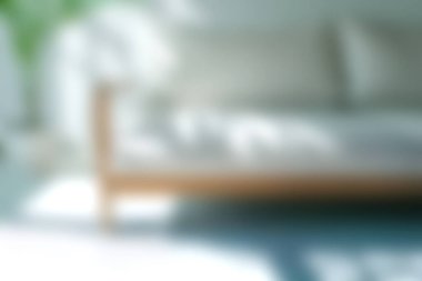 Bu yumuşak odak görüntüsü, parlak, minimalist bir oturma odasında rahat ve rahat bir atmosfer sunan şık ve modern bir kanepeyi gösteriyor..