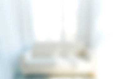 Yumuşak odaklı bir görüntü, rahat beyaz bir kanepe ile parlak bir iç mekan sergiliyor, doğal ışığı davet ediyor, ve sakin bir atmosfer rahatlama ve modern yaşam için mükemmel..