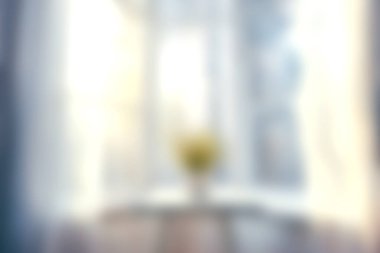 Yumuşak doğal ışığın bir pencereden süzüldüğü, parlak sarı çiçekli bir vazoyla bir masayı aydınlattığı, huzurlu bir ortam yarattığı huzurlu bir manzara..