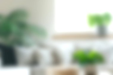 Canlı yeşil bitkilerin, yumuşak tekstil ürünlerinin ve minimalist dekorun sergilendiği rahat bir oturma odası. Bu davet mekanı rahatlamayı ve sıcaklığı teşvik eder..