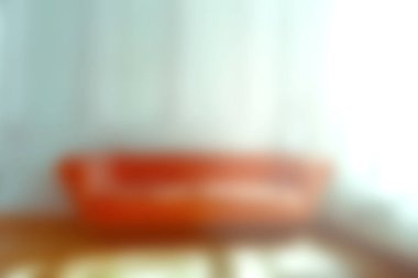 Sıcak bir oturma odasında, perdelerin arasından süzülen yumuşak doğal ışıkla aydınlatılmış canlı turuncu bir kanepe var. Sıcak ve davetkar bir atmosfer yaratıyor..