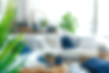 Parlak ve havadar bir oturma odasında yeşil bitkiler, rahat tekstil ve modern bir evde rahatlatıcı ve davetkar bir atmosfer yaratan yumuşak bir ışık sergileniyor..