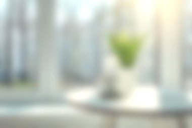 Parlak bir pencerenin yanında bulanık yeşil bir bitki barındıran sakin, yumuşak bir iç mekan. Rahatlama ve rahatlama için ideal bir ortam yaratıyor..