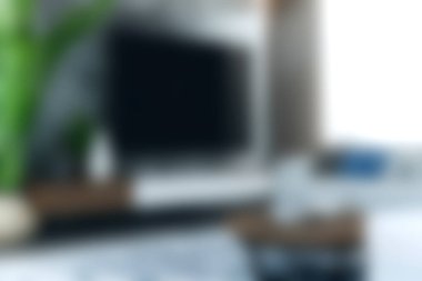 Bu resim, geniş ekran televizyonu olan, aydınlık ve davetkar bir atmosferde minimalist tasarım unsurları sergileyen modern bir oturma odasını içeriyor..