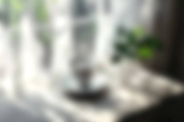 Yumuşak bir güneş ışığının, pencere kenarındaki yeşil bir bitkinin üzerinde parladığı sakin bir ortam yaratarak ev dekorasyonu ve rahatlama için mükemmel bir ortam yaratıyor..