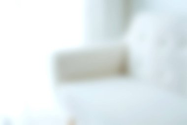 Çağdaş oturma odası kanepesinin bulanık bir görüntüsü. Parlak doğal ışıkla yıkanmış. Kapalı bir mekanda rahatlık ve tarz sergiliyor..