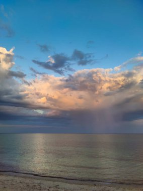 Okyanus ufkunun üzerinde gökkuşağı olan dramatik bulutlu gökyüzü