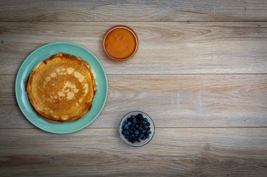 Tahta tabakta altın krep ve taze yaban mersini. Ev yapımı tatlı yemek konsepti, kahvaltı, brunch veya tatlı için mükemmel. Kırsal yemek fotoğrafçılığı.