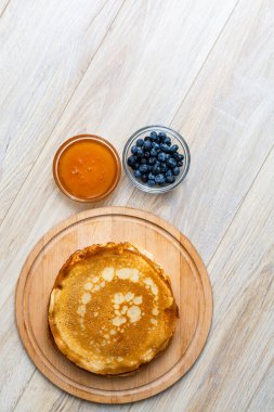 Tahta tabakta altın krep ve taze yaban mersini. Ev yapımı tatlı yemek konsepti, kahvaltı, brunch veya tatlı için mükemmel. Kırsal yemek fotoğrafçılığı.