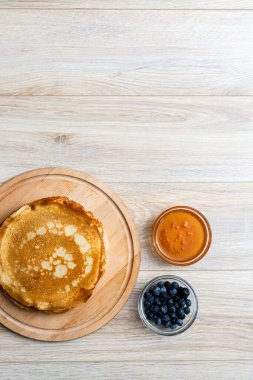 Tahta tabakta altın krep ve taze yaban mersini. Ev yapımı tatlı yemek konsepti, kahvaltı, brunch veya tatlı için mükemmel. Kırsal yemek fotoğrafçılığı.
