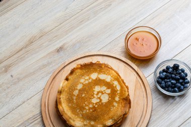 Tahta tabakta altın krep ve taze yaban mersini. Ev yapımı tatlı yemek konsepti, kahvaltı, brunch veya tatlı için mükemmel. Kırsal yemek fotoğrafçılığı.