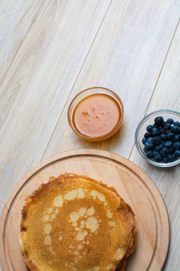 Tahta tabakta altın krep ve taze yaban mersini. Ev yapımı tatlı yemek konsepti, kahvaltı, brunch veya tatlı için mükemmel. Kırsal yemek fotoğrafçılığı.