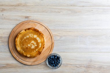 Tahta tabakta altın krep ve taze yaban mersini. Ev yapımı tatlı yemek konsepti, kahvaltı, brunch veya tatlı için mükemmel. Kırsal yemek fotoğrafçılığı.