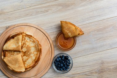 Tahta tabakta altın krep ve taze yaban mersini. Ev yapımı tatlı yemek konsepti, kahvaltı, brunch veya tatlı için mükemmel. Kırsal yemek fotoğrafçılığı.