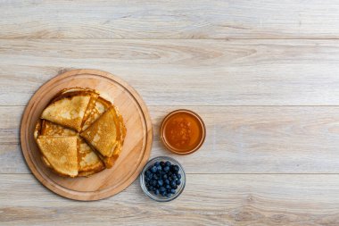 Tahta tabakta altın krep ve taze yaban mersini. Ev yapımı tatlı yemek konsepti, kahvaltı, brunch veya tatlı için mükemmel. Kırsal yemek fotoğrafçılığı.