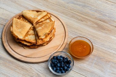 Tahta tabakta altın krep ve taze yaban mersini. Ev yapımı tatlı yemek konsepti, kahvaltı, brunch veya tatlı için mükemmel. Kırsal yemek fotoğrafçılığı.