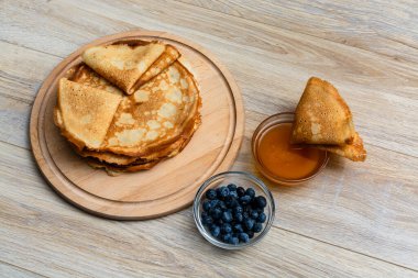 Tahta tabakta altın krep ve taze yaban mersini. Ev yapımı tatlı yemek konsepti, kahvaltı, brunch veya tatlı için mükemmel. Kırsal yemek fotoğrafçılığı.