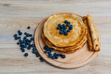 Tahta tabakta altın krep ve taze yaban mersini. Ev yapımı tatlı yemek konsepti, kahvaltı, brunch veya tatlı için mükemmel. Kırsal yemek fotoğrafçılığı.