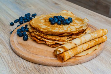 Tahta tabakta altın krep ve taze yaban mersini. Ev yapımı tatlı yemek konsepti, kahvaltı, brunch veya tatlı için mükemmel. Kırsal yemek fotoğrafçılığı.
