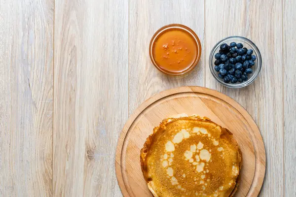 Tahta tabakta altın krep ve taze yaban mersini. Ev yapımı tatlı yemek konsepti, kahvaltı, brunch veya tatlı için mükemmel. Kırsal yemek fotoğrafçılığı.