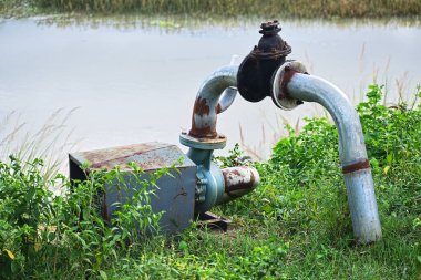 Eski paslı su motoru ve borusu bir tarım sahasında