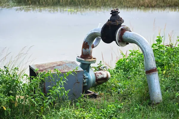 Eski paslı su motoru ve borusu bir tarım sahasında