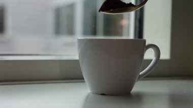 Doğal ışığı olan bir pencerenin yakınındaki fincana dökülen kahvenin yavaş çekim videosu. Kahve reklamları ve yemek reklamları için ideal..