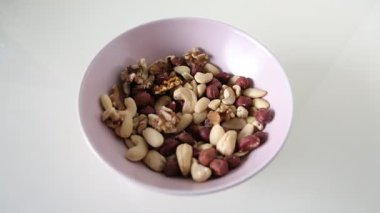 Yukarıdan daha fazla fındık düşerken, fındık dolu bir kasenin üst görüntüsü. Minimalist sağlıklı gıda konsepti, yemek, diyet ve atıştırmalıkla ilgili içerik için ideal.