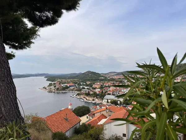 Kırmızı çatılı binaları ve sakin bir körfeze bakan yemyeşil yemyeşil manzaralı kıyı kasabası..